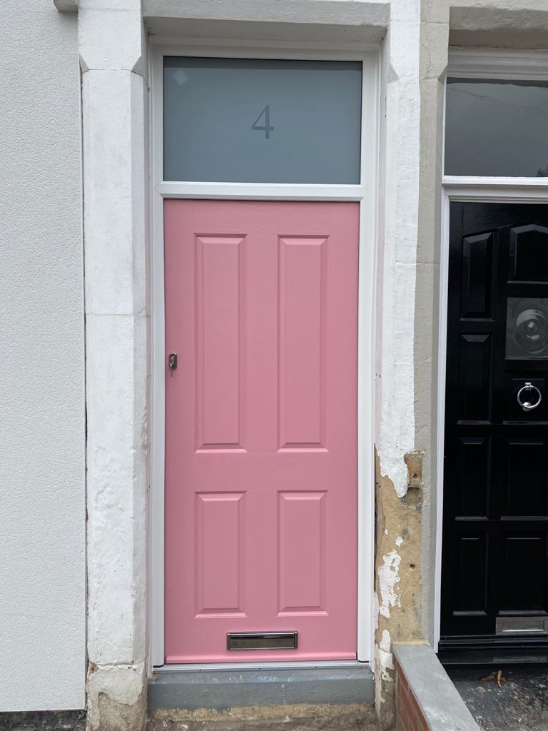Pink panelled front door with a fanlight above it