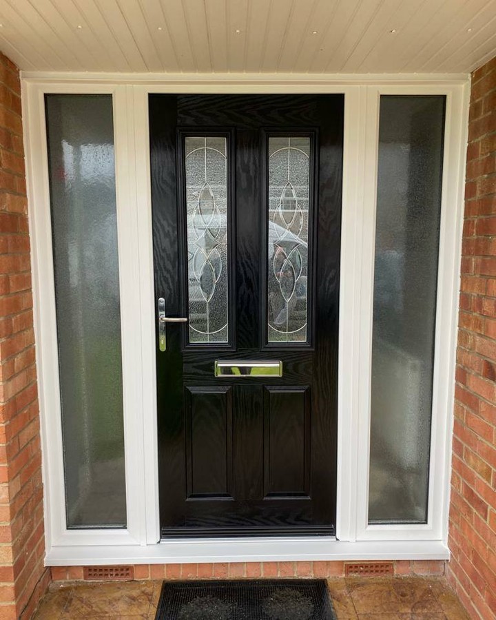 Black front door with leaded glazing and frosted side panels in a white frame